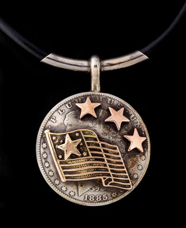 AN ARNOLD GOLDSTEIN SILVER DOLLAR AND 10K PENDANT