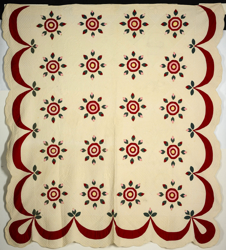 AN ANTIQUE RED AND GREEN APPLIQUED QUILT