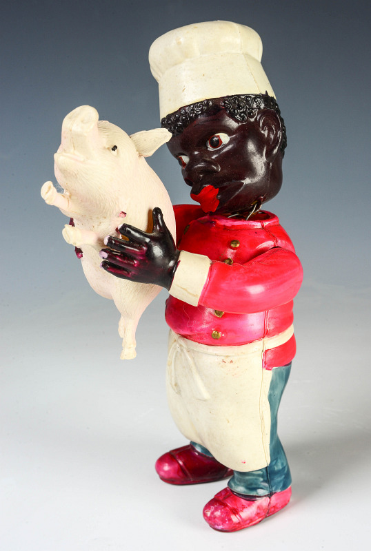 A CIRCA 1930 CELLULOID TOY BLACK CHEF WITH PIG 