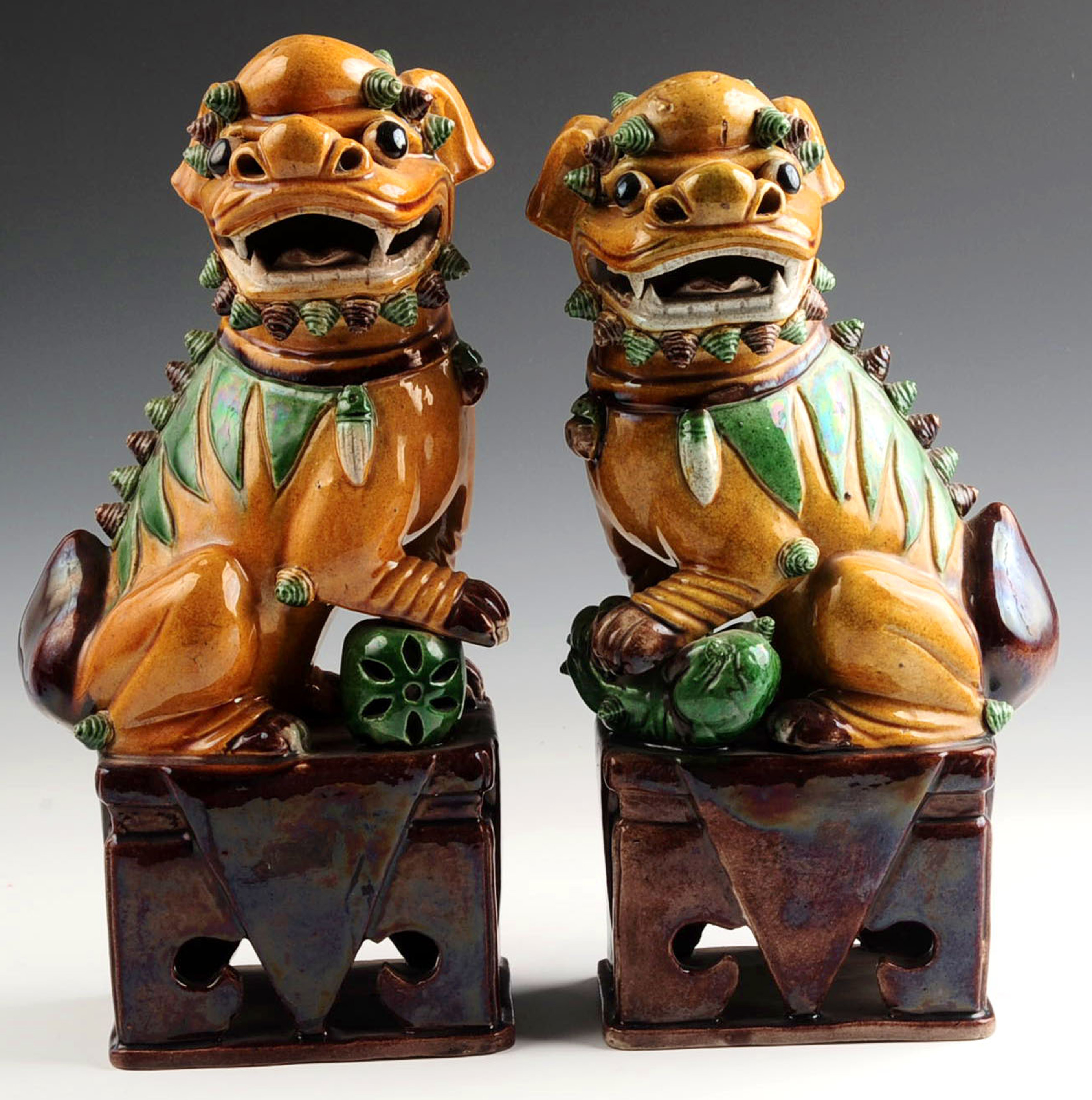 A PAIR OF EARLY 20TH CENTURY GLAZED FOO DOG FIGURE