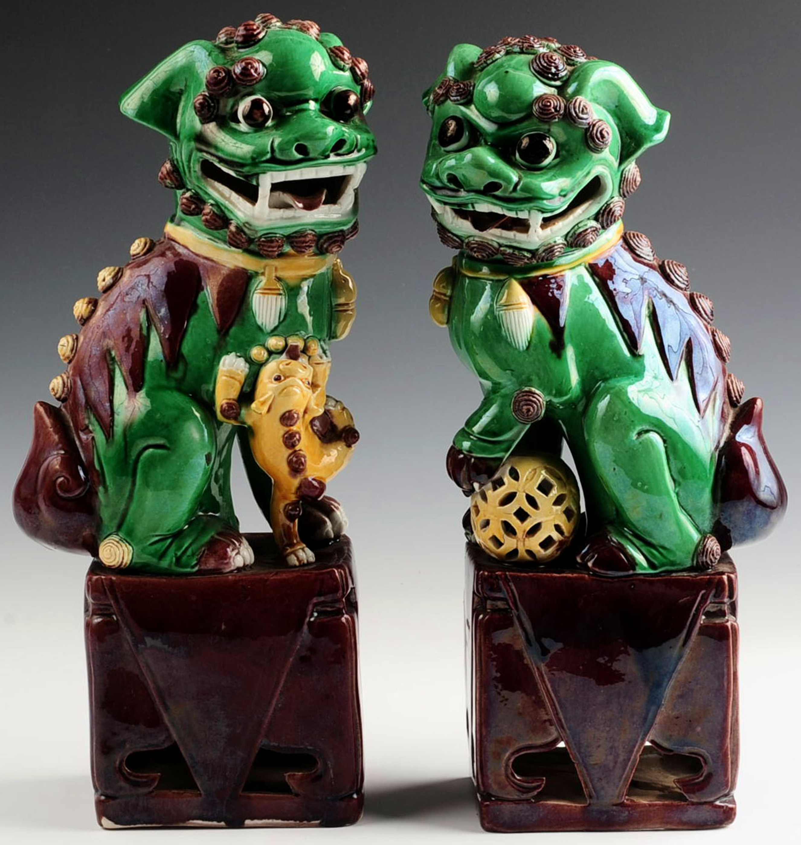 A PAIR OF EARLY 20TH CENTURY GLAZED FOO DOG FIGURE