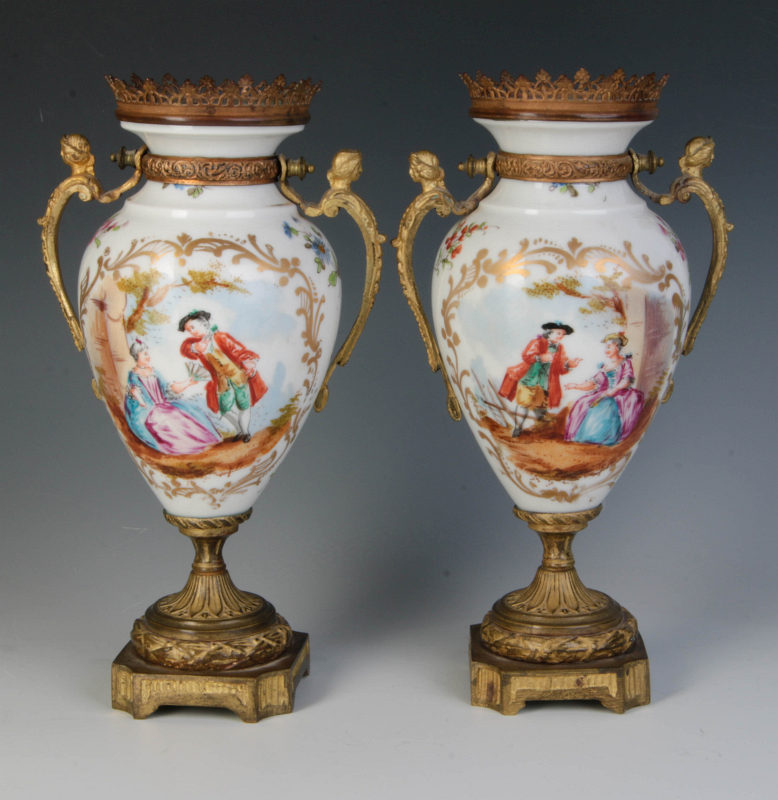 A PAIR OF PORCELAIN URNS IN METAL MOUNTS