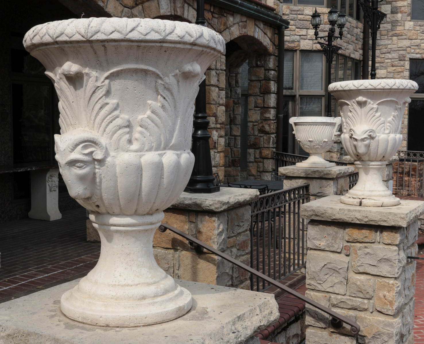 A PAIR OF CAST STONE URNS WITH RAM'S HEADS