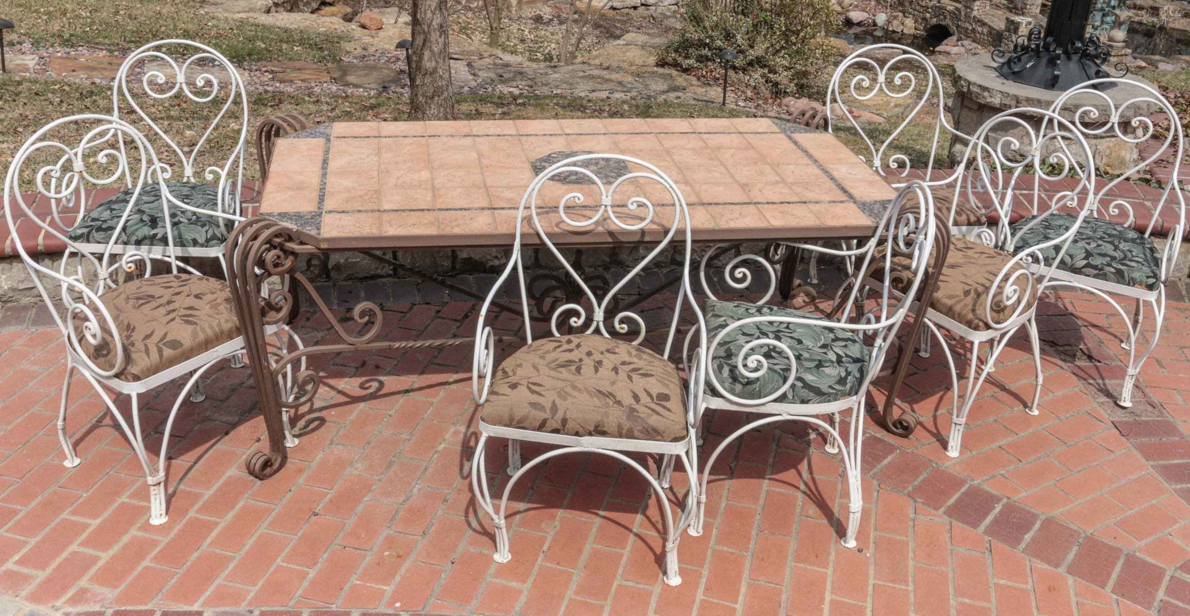 AN EIGHT PIECE IRON PATIO SET WITH TILE TOP TABLE