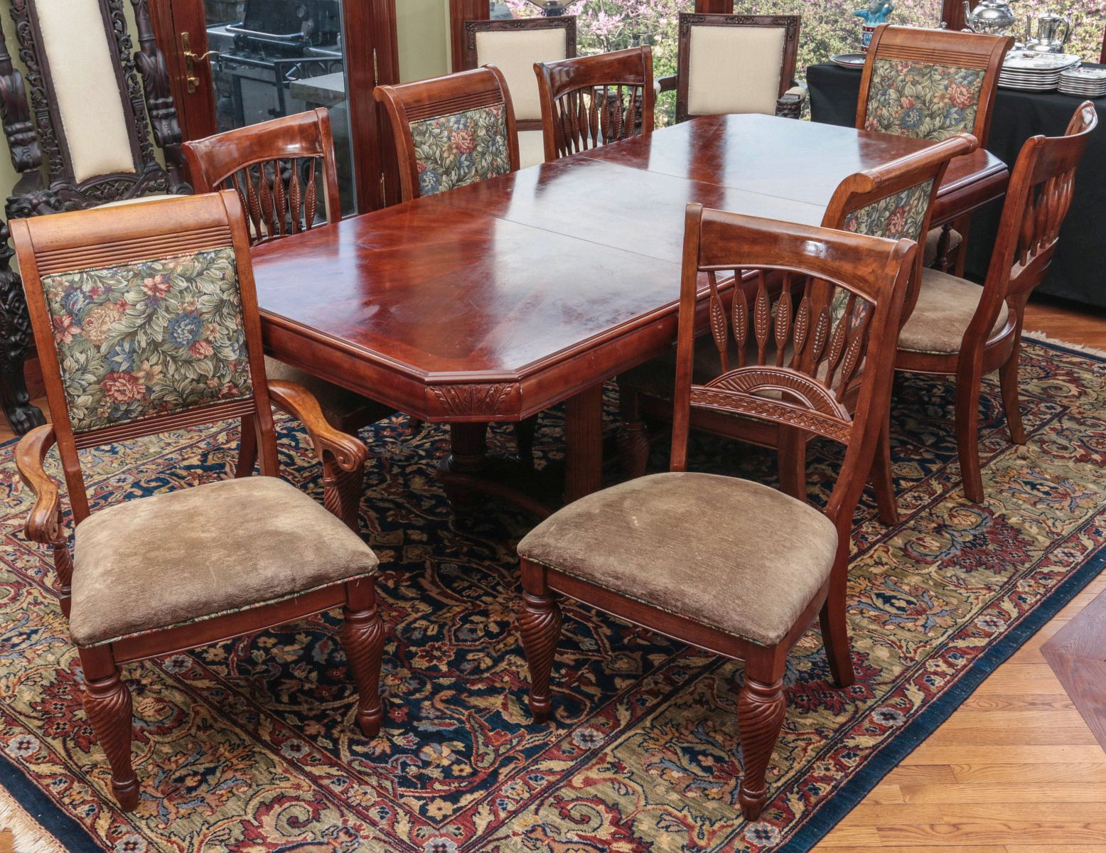 A CARVED MAHOGANY DINING TABLE WITH EIGHT CHAIRS
