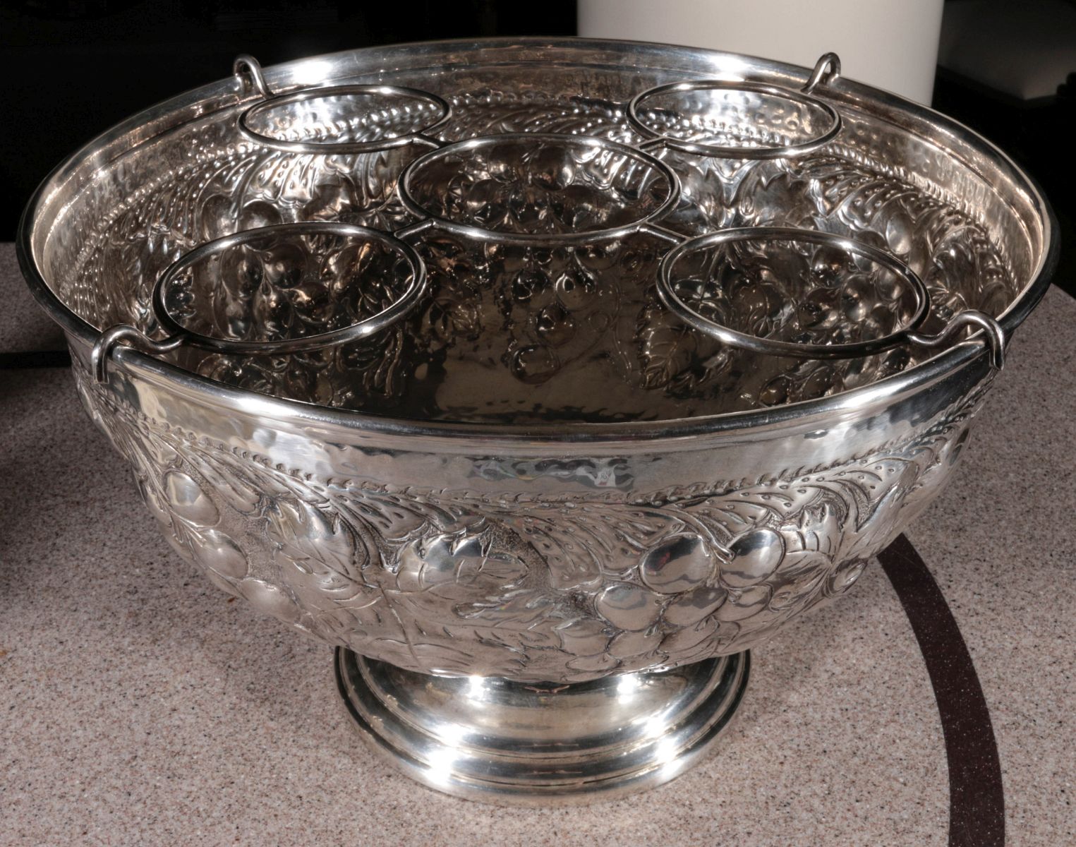 A LARGE EMBOSSED WHITE METAL PUNCH BOWL