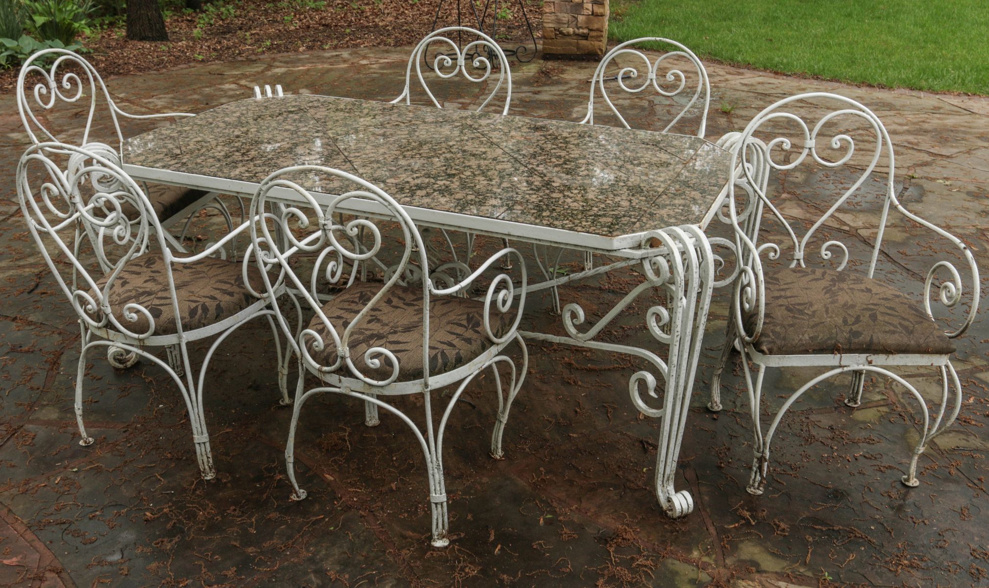 A SEVEN PIECE IRON PATIO SET WITH GRANITE TILE TOP