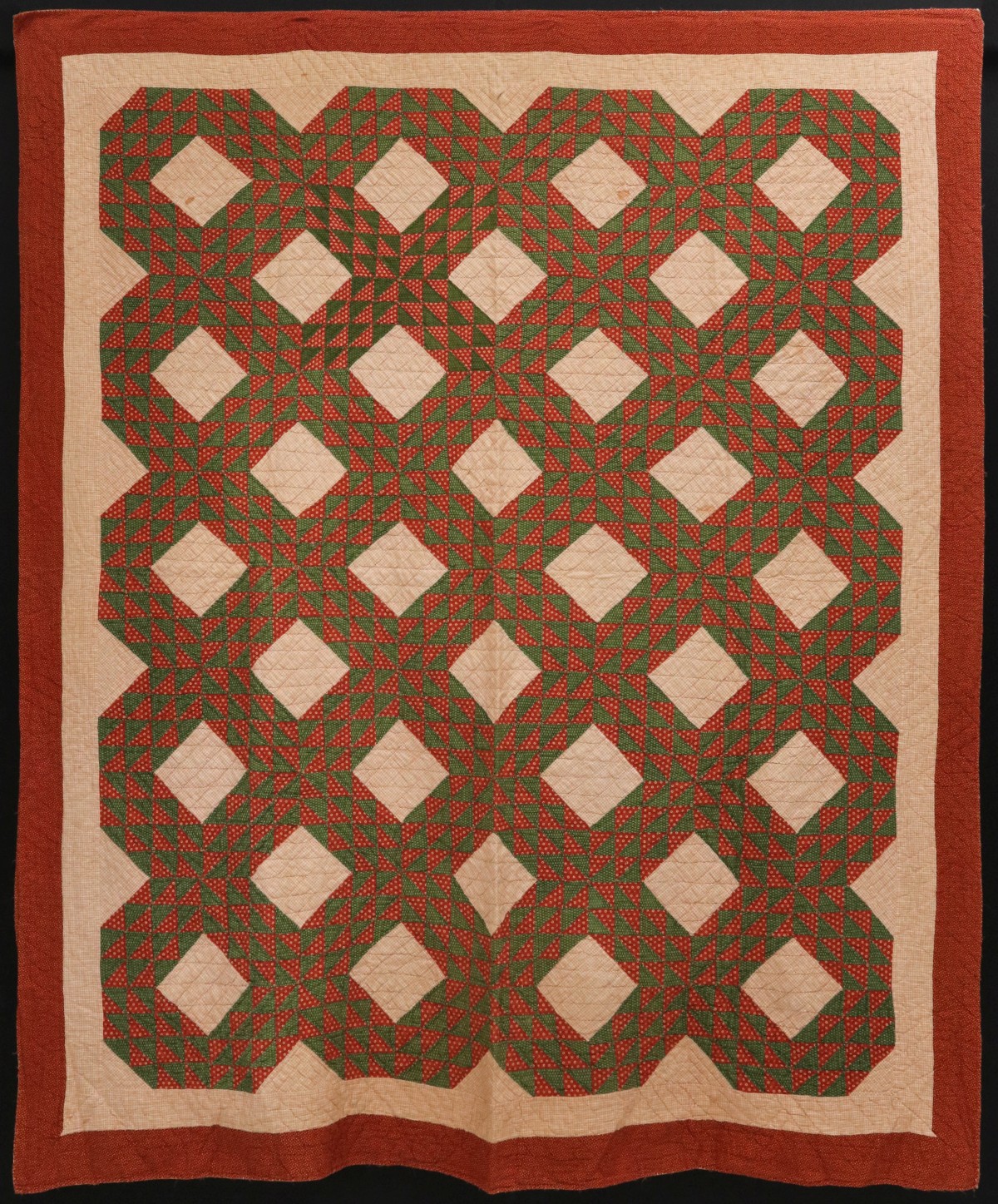 AN ANTIQUE 'OCEAN WAVE' PATTERN QUILT IN RED AND GREEN