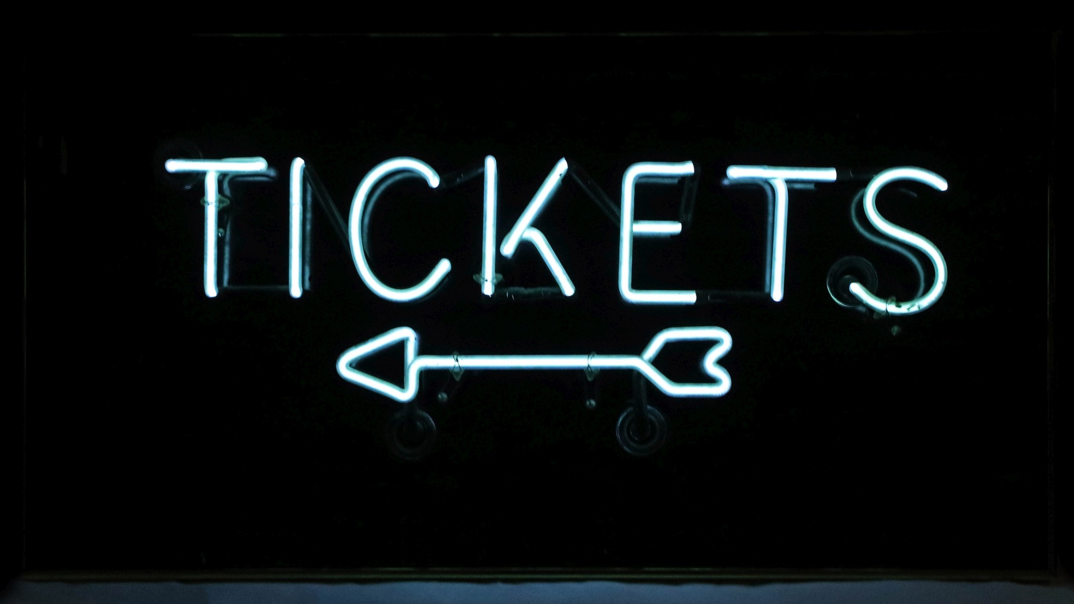 A NEON LETTER SIGN WITH ARROW AND THE WORD 'TICKETS'